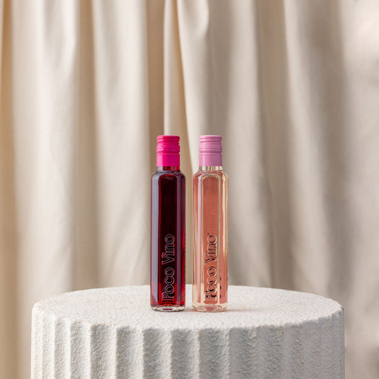 Two bottles of Toco Vino on a textured surface with a neutral background