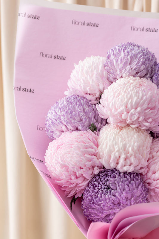 Bouquet of pink and purple flowers with a pink floral design on the paper wrapping.